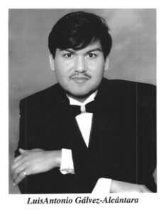 a black and white photo of tenor Luis Galvez, a Latino man with a mustache sporting a tuxedo and bow tie as he folds his arms and looks seriously towards the camera