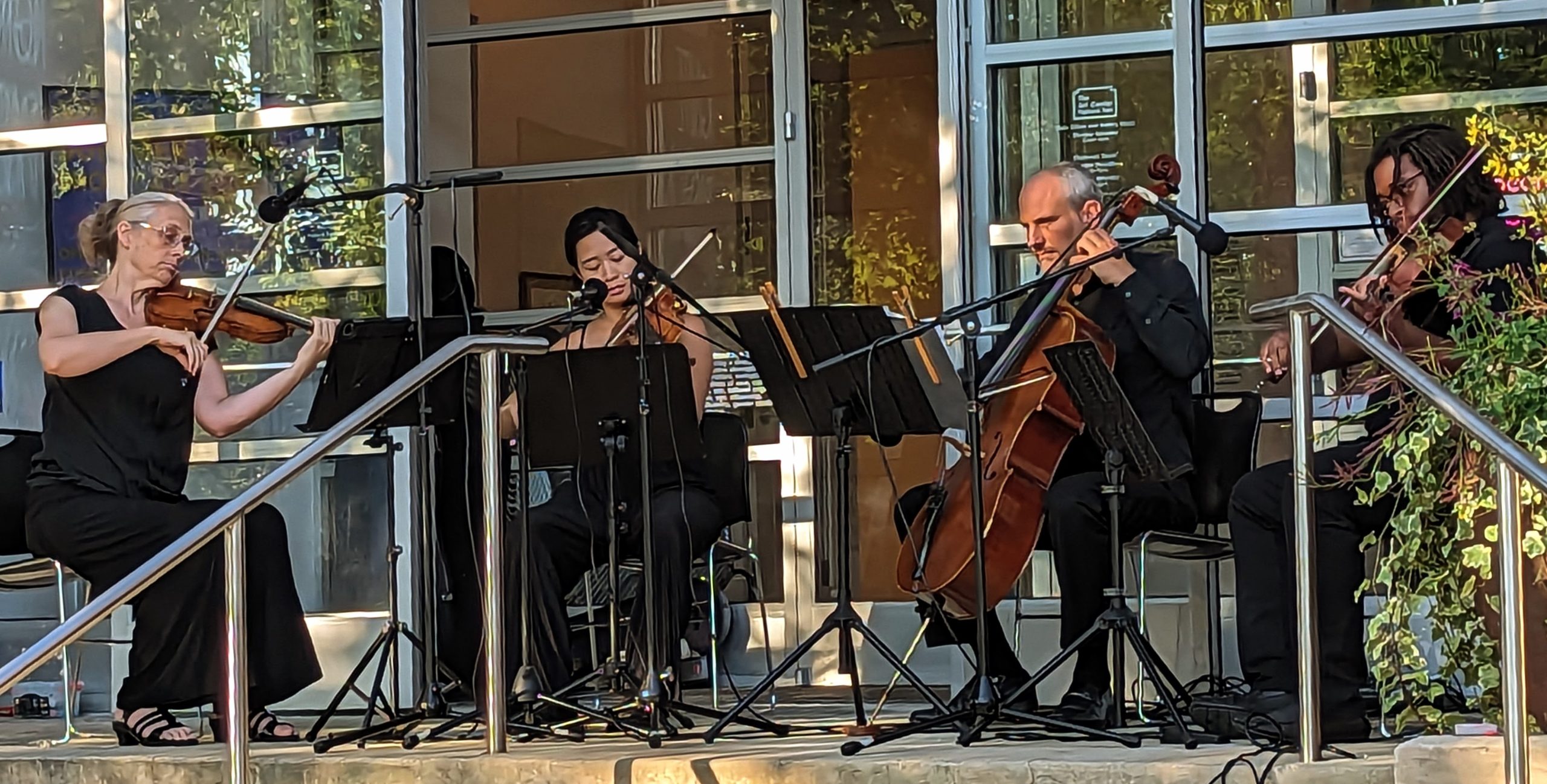 Crossing Borders Music string quartet plays before museum's glass windows.